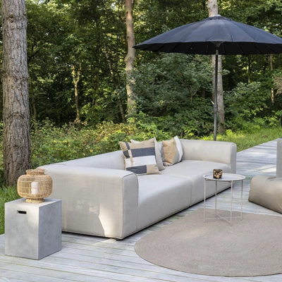 Ljus trädgårds-lounge-soffa på terrass omgiven av loungebord, parasoll och matta