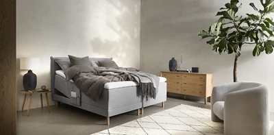 Sovrum med elevationssäng, byrå, fåtölj och stor växt