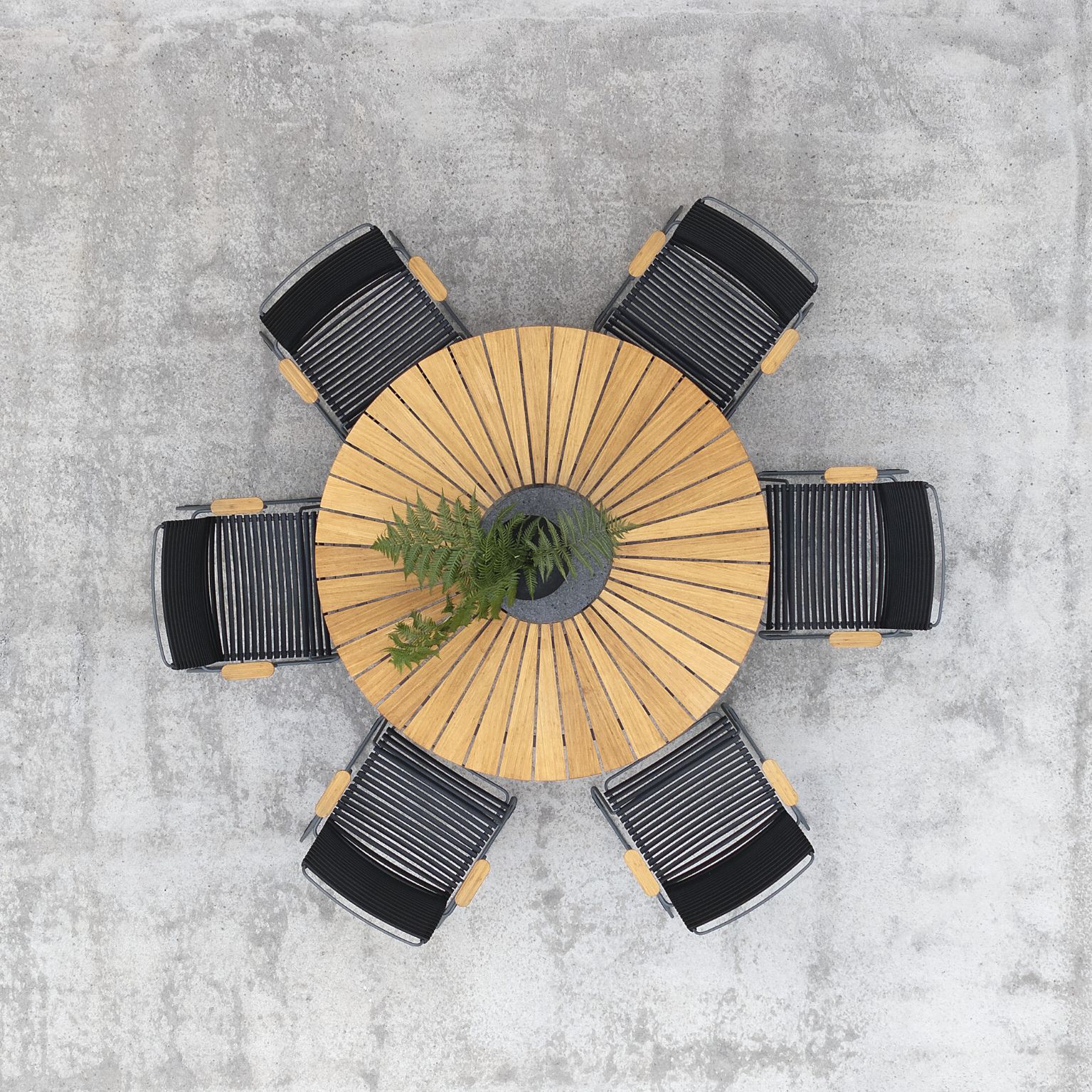 Runt trädgårdsbord med svarta stolar sett uppifrån