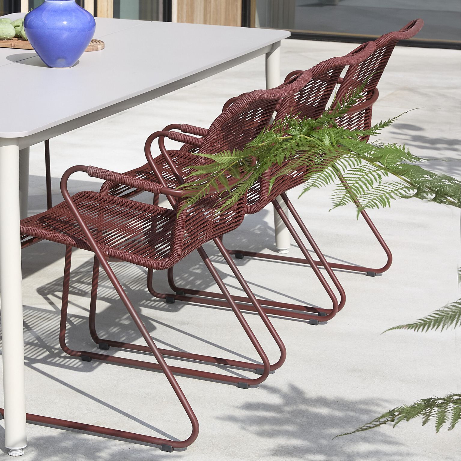 Röda trädgårdsstolar vid grått trädgårdsbord