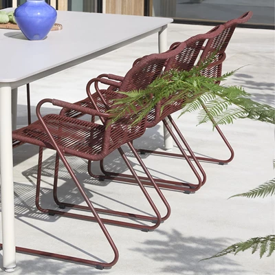 Röda trädgårdsstolar vid grått trädgårdsbord