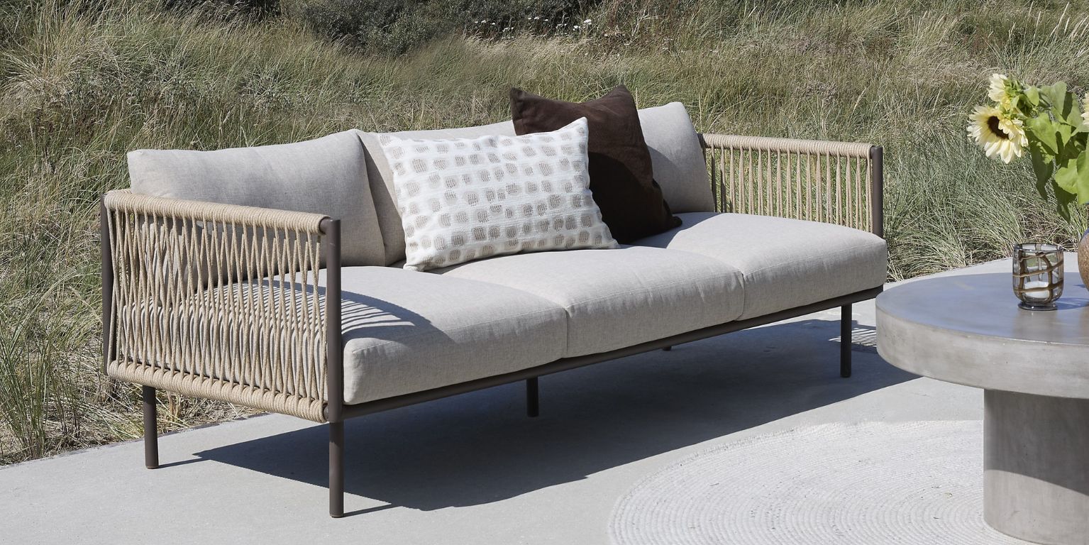 Loungesoffa i flätad design som står på en betonggrund