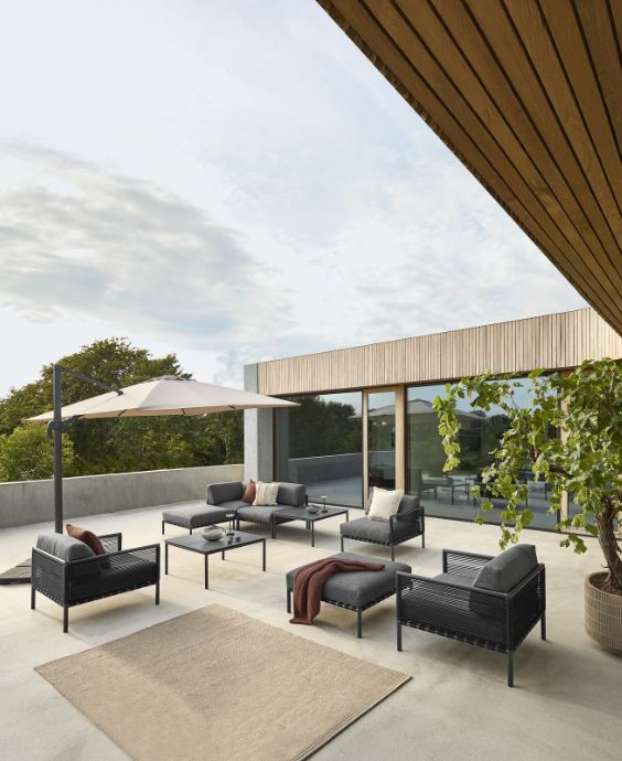 Modern terrass med loungemöbler i mörk stomme och grå dynor