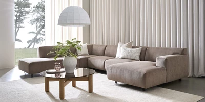 Vesta.jpg Minimalistiskt vardagsrum med en stor, beige u-soffa i centrum.