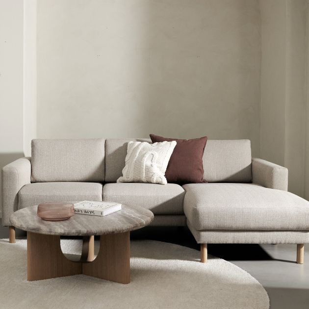 Modulsoffa i beige med träbord i ljus vardagsrumsmiljö.