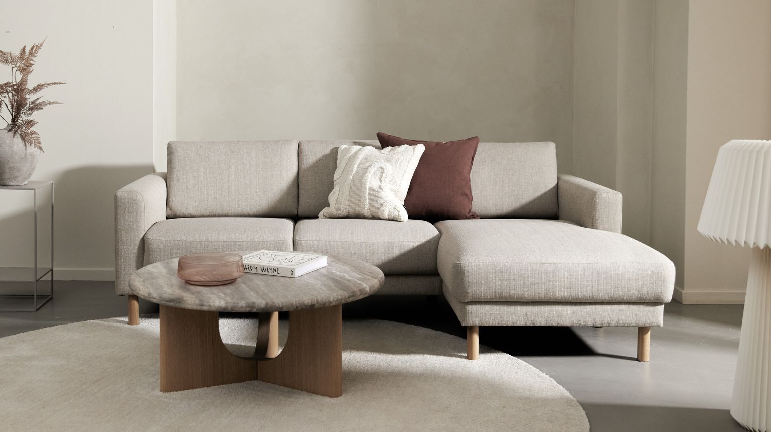 3-sits chaiselongsoffa i ljusbeige tillsammans med soffbord och matta.