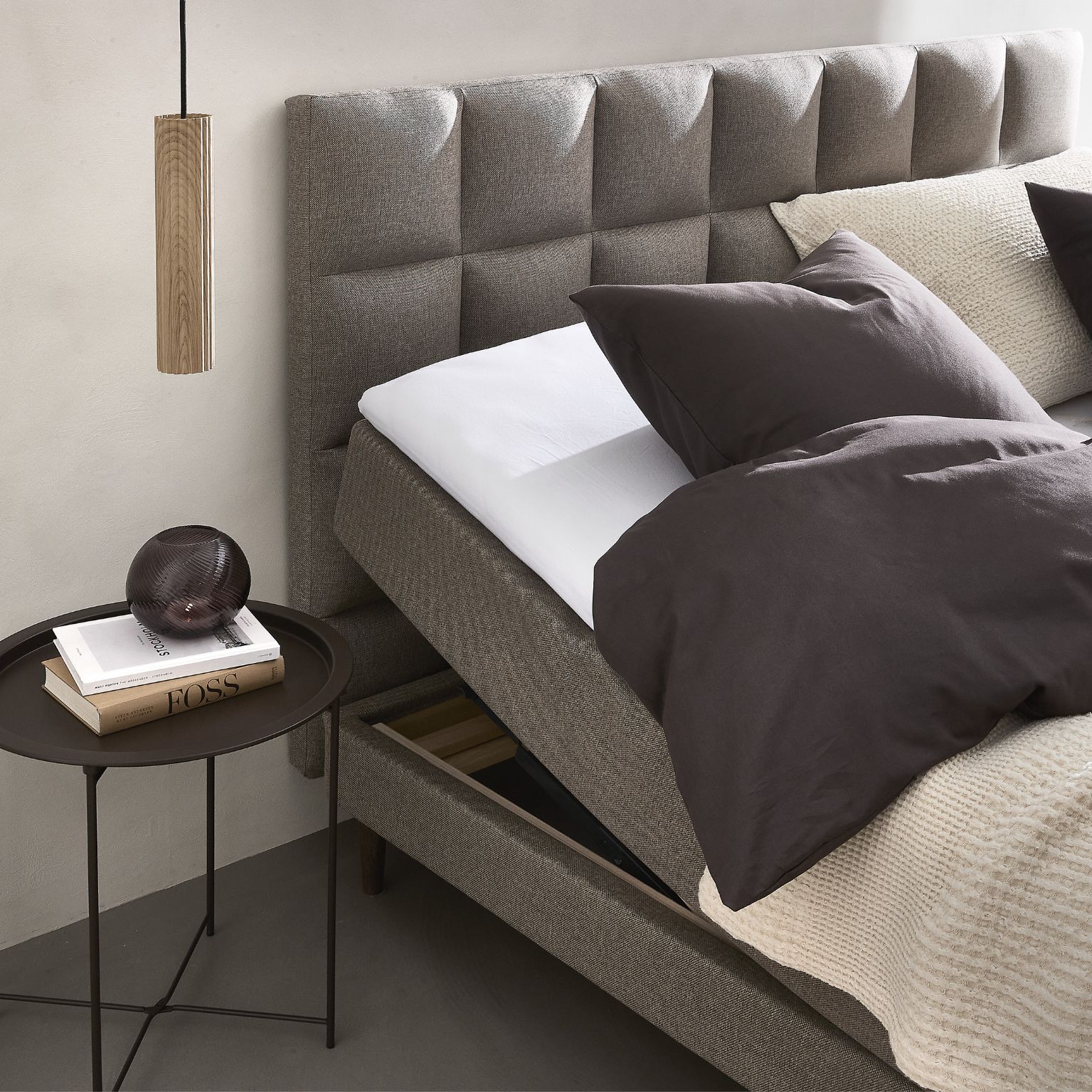 Ställbar säng med sänggavel och sängbord med böcker