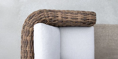 Lounge-soffa i brun polyrattan med ljusgrå dynor.