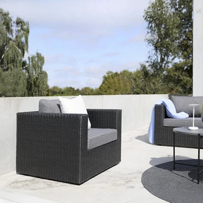 Svart loungefåtölj i polyrattan stående på en terrass