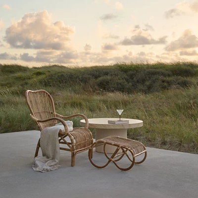 Fåtölj med fotpall i naturrattan med solnedgång i bakgrunden