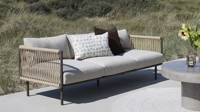 Loungesoffa med grå dynor och flätning på sidorna.