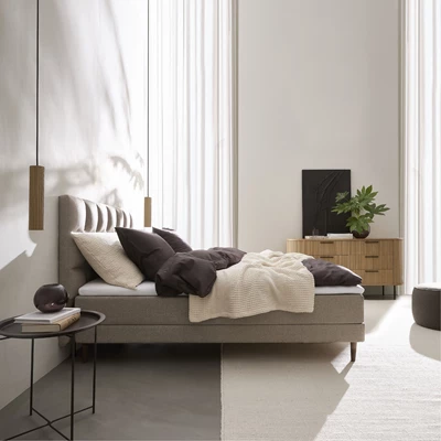 Ljust sovrum med ljusbrun ställbar säng och runt sängbord