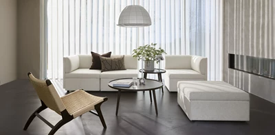 Ljust vardagsrum med soffa, fåtölj, soffbord och vit pendellampa.