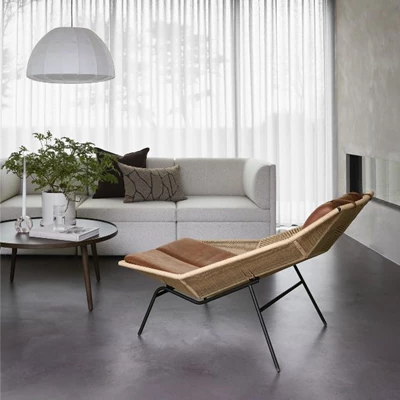 Ljust och nordiskt vardagsrum med vit soffa och en brun fåtölj.