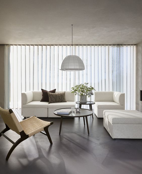 Ljust och nordiskt vardagsrum med vit soffa, fåtölj och soffbord.