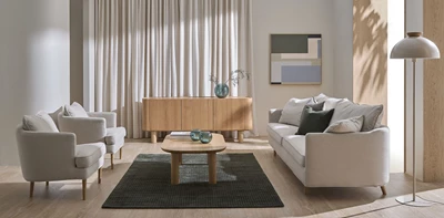 Ljust vardagsrum med soffa, fåtöljer, soffbord och sideboard.