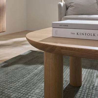 Närbild av ben på soffbord i trä med böcker ovanpå.