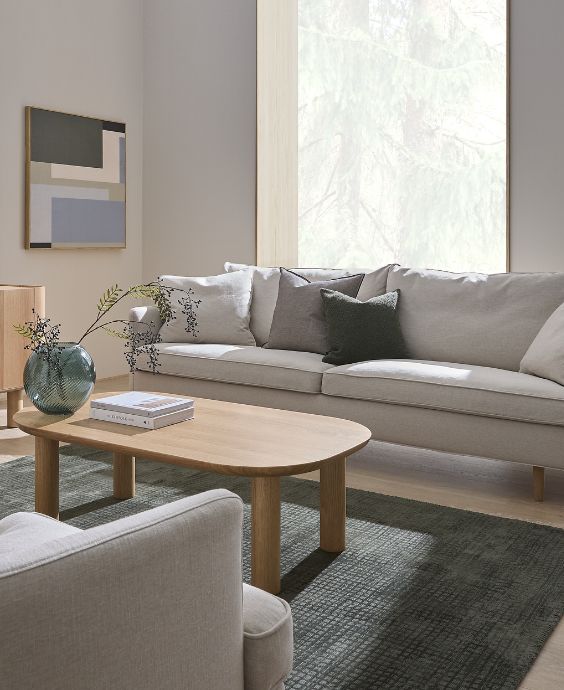 Ljust vardagsrum med soffa, soffbord och fåtölj.