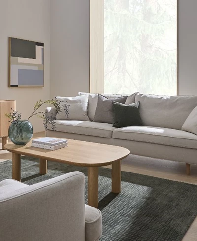 Ljust vardagsrum med soffa, soffbord och fåtölj.