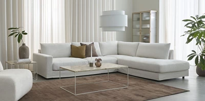 Ljust vardagsrum i nordisk stil med en vit hörnsoffa i centrum.