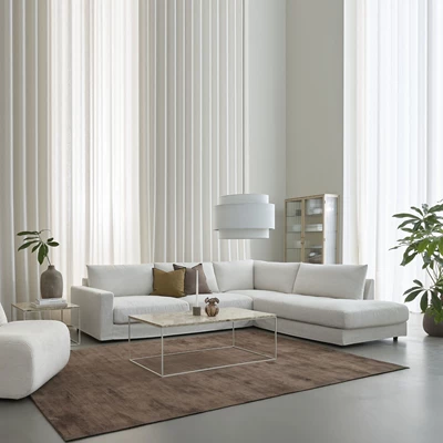 Ljust vardagsrum i nordisk stil med en vit hörnsoffa i centrum.