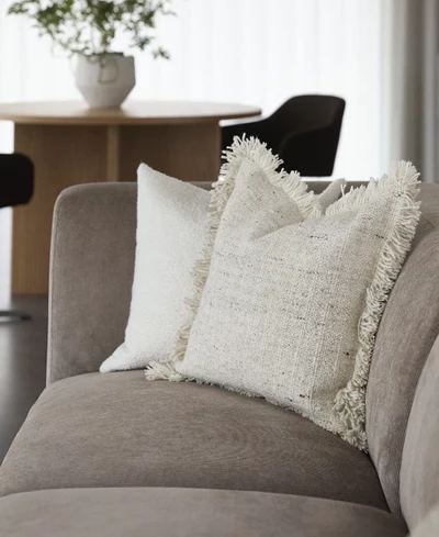 Närbild av soffa med vita kuddar.