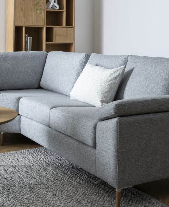 Grå soffa med armstöd och kuddar.