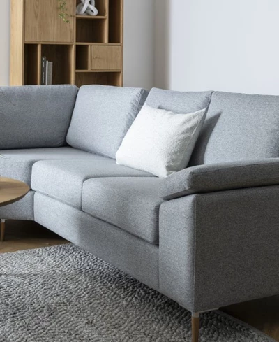 Grå soffa med armstöd och kuddar.