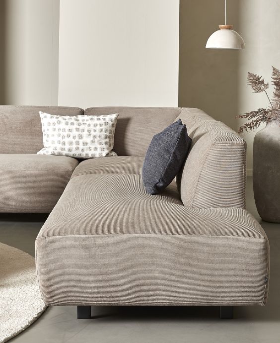 Chaiselongsoffa i taupe i vardagsrum med en ljus taklampa.