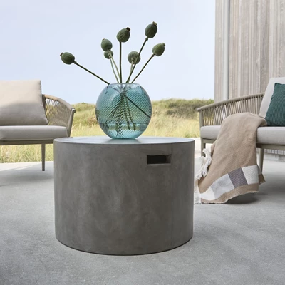 Runt loungbord i grå fibercement med en vas ovanpå