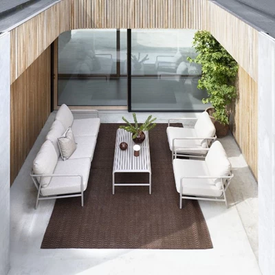 Terrassset sett uppifrån med ljusa trädgårdsmöbler och röd matta