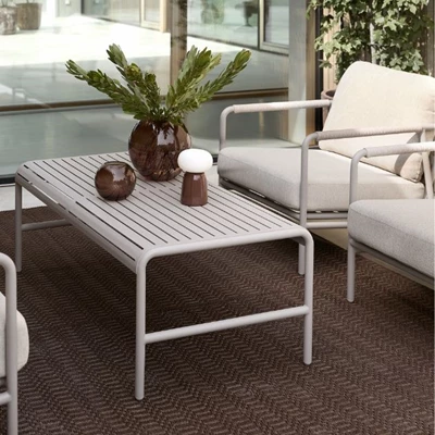 Närbild av ett loungebord i grått som står på en röd matta på terrassen