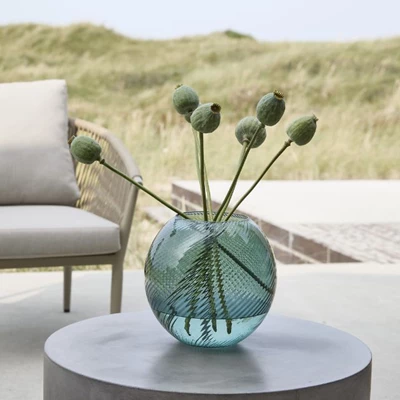 Rund vas i turkos stående på grått loungebord