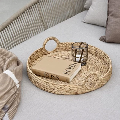 Bricka i flätat material på grå loungesäng