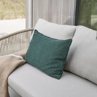 Kudde med grönt överdrag på grå loungesoffa