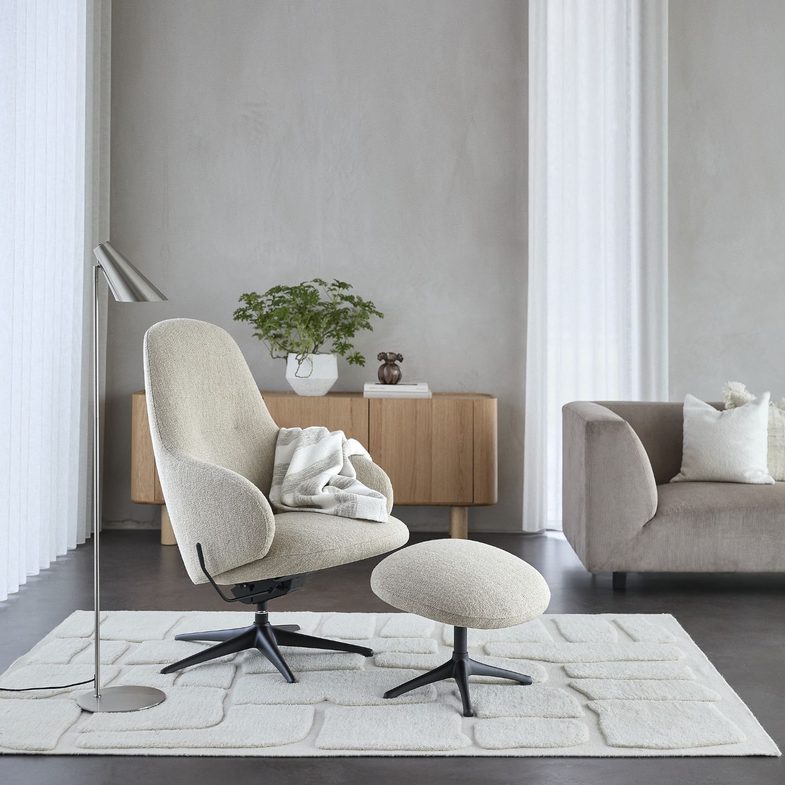 Vit fåtölj med pall stående ovanpå vit matta