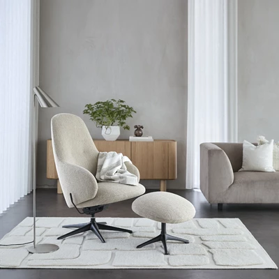 Vit fåtölj med pall stående ovanpå vit matta