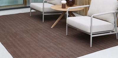 Röd utomhusmatta tillsammans med två vita loungestolar