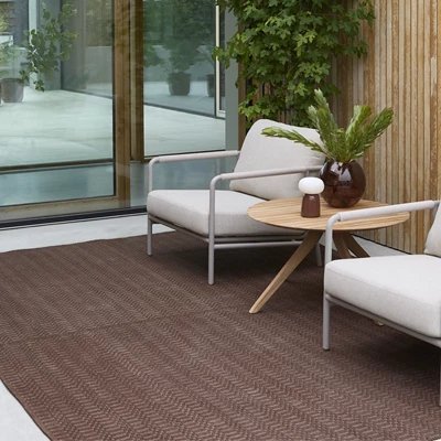 Röd utomhusmatta tillsammans med två vita loungestolar