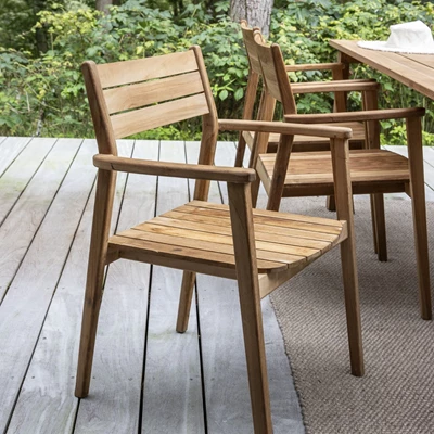 Trädgårdsstol i trä stående vid trädgårdsbord i samma material