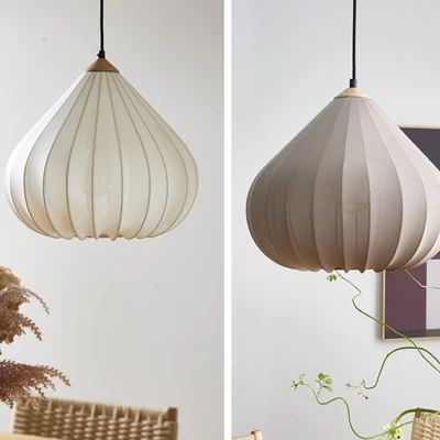 Två pendellampor i vitt respektive taupe, upphängda med svart sladd.