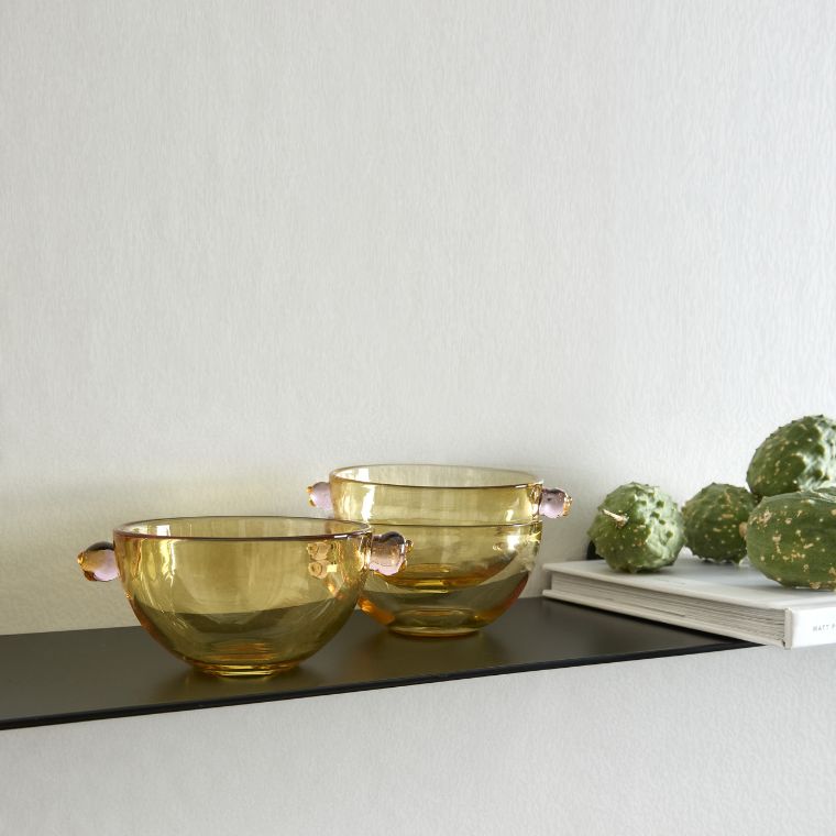 Gula, genomskinliga skålar stående på svart hylla
