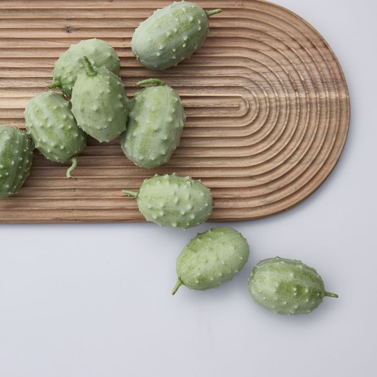 Räfflad skärbräda i trä med gröna frukter ovanpå