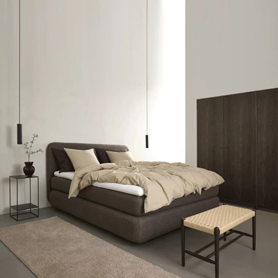 Brun kontinentalsäng i sovrum med bänk framför