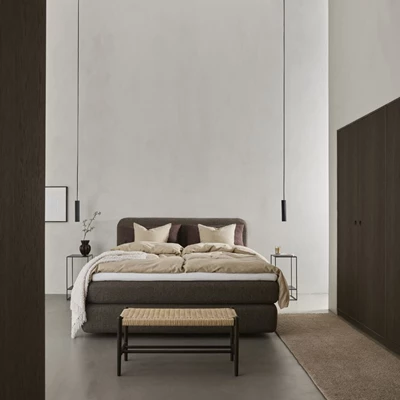 Brun kontinentalsäng i sovrum med svarta nattduksbord och bänk