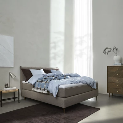 Kontinentalsäng med ljusblått sänglinne i ljust sovrum