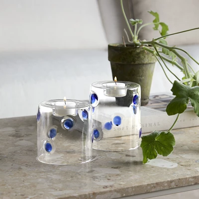 Två värmeljushållare i glas med blå prickar