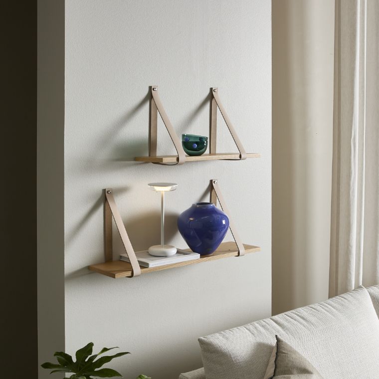 2 vägghyllor med läderremmar hängande på väggen.