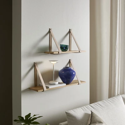 Valentino.jpg (1) 2 vägghyllor med läderremmar hängande på väggen.