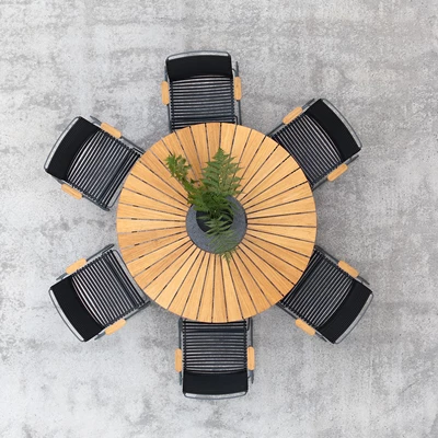 Bild tagen ovanifrån på ett runt utebord i teakträ, omgivet av sex stycken stolar med svarta plastlameller och trähandtag.